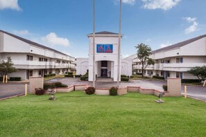 A hotel with a central entrance, multiple floors, and a parking area. - 1 King Bed | Smoking, Micfridge (Irving TX)