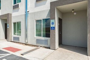 En bygningseingang med et skilt der angiver reserverede parkeringspladser, et skilt for handicapvenlig transport og en dør, der fører til en parkeringsplads.
