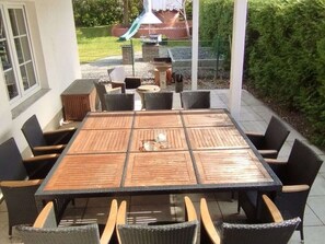 An outdoor patio with a square table surrounded by chairs, a small round table, and a grill. - Holiday Home With 5 Bedrooms (Ueckermuende)