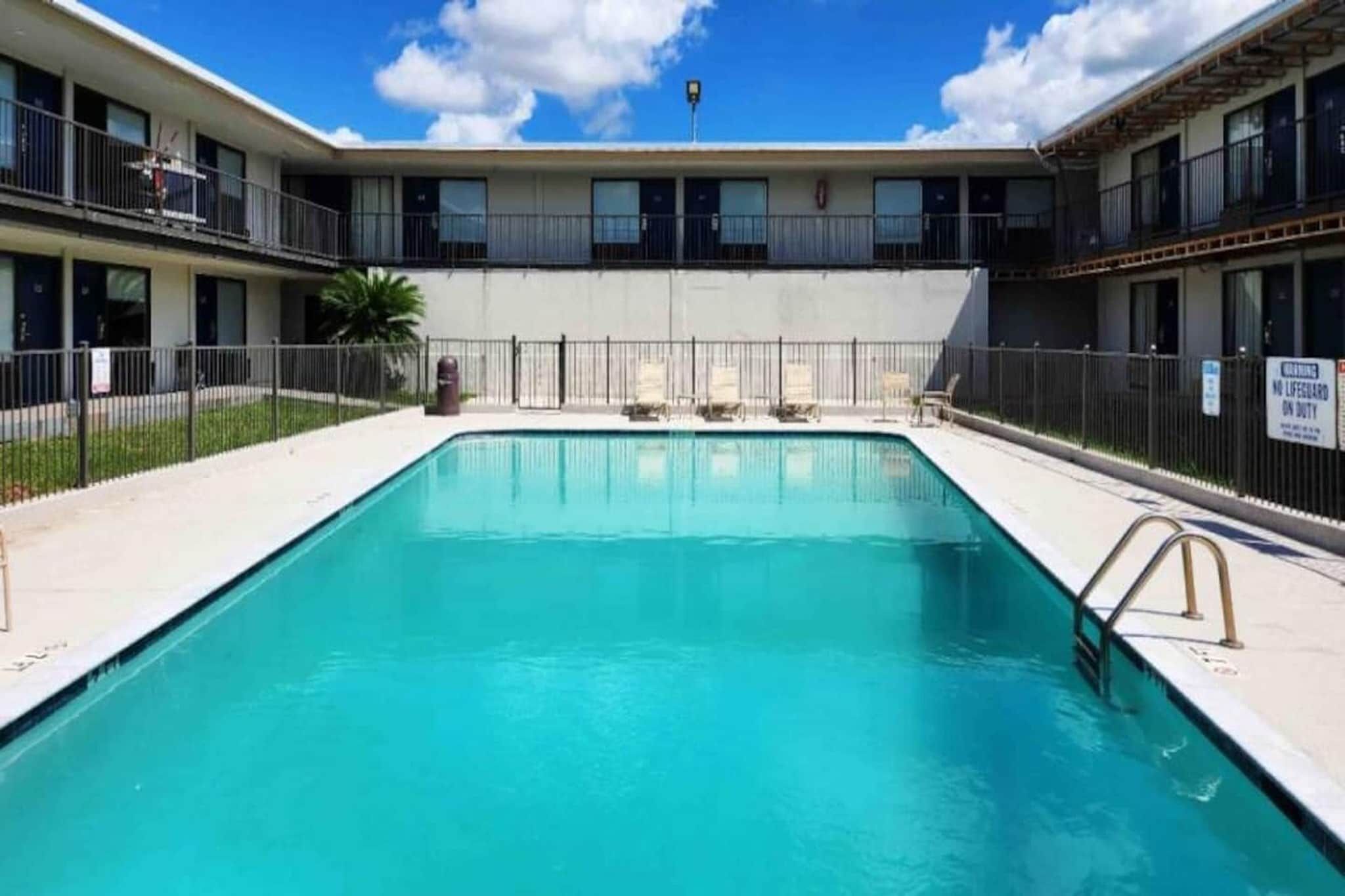 A rectangular swimming pool with a metal ladder on one side, surrounded by a fence.