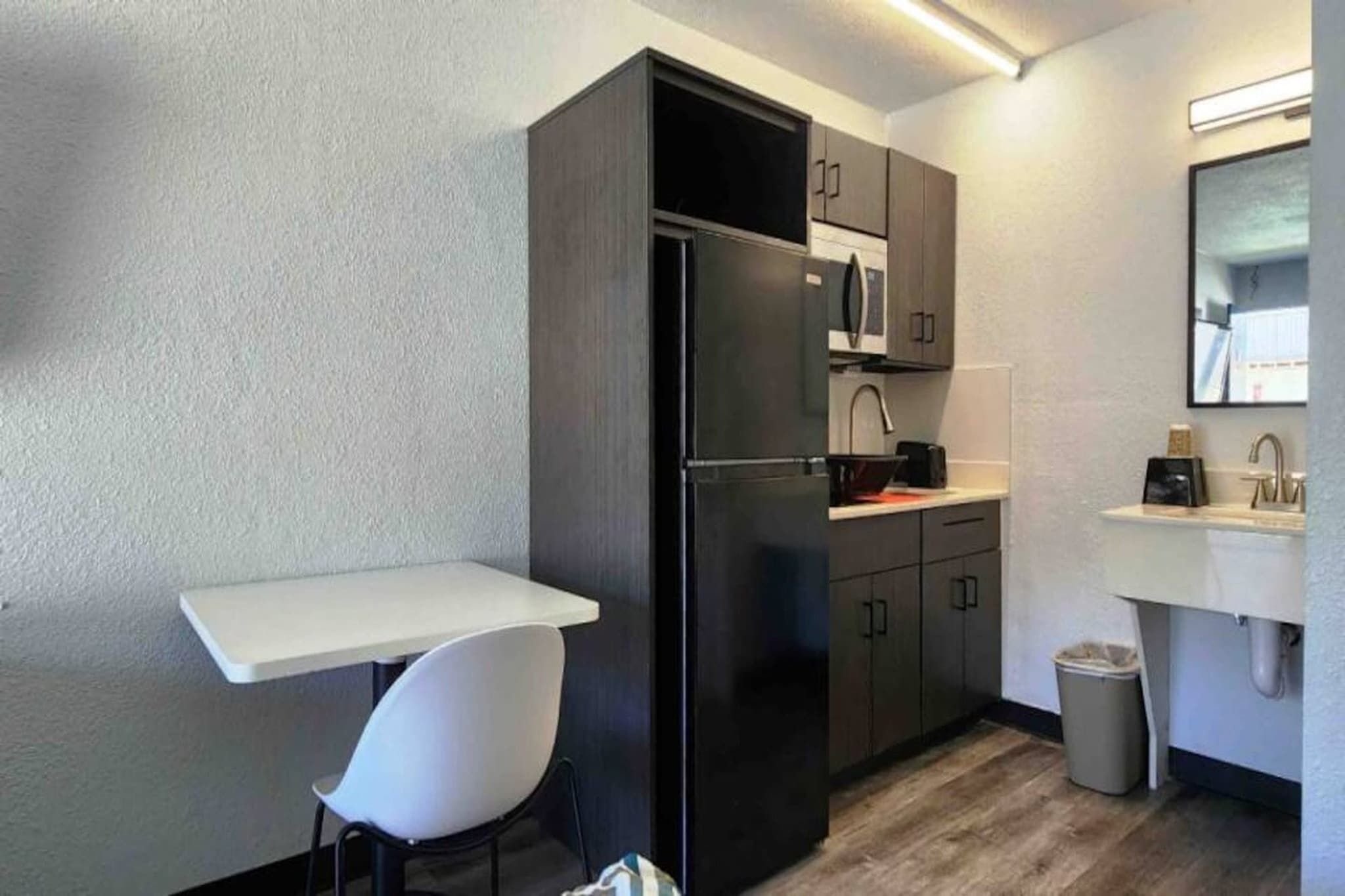 A compact kitchenette with a refrigerator, a sink, and a small dining area.