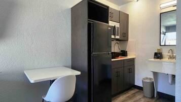 A compact kitchenette with a refrigerator, a sink, and a small dining area.
