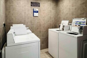 A laundry room with stacked washing machines and dryers, a sign indicating responsibility for unattended items, and a notice about parking. - 1 King Bed | Mobil Access Tub Nsmk Kitchen (Alvin)