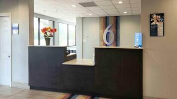 A reception area with a reception desk, a large number '6' on the wall, and a window with flowers.