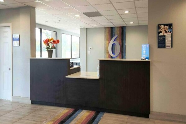 A reception area with a reception desk, a large number '6' on the wall, and a window with flowers.