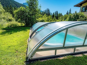 A greenhouse structure with a transparent roof, surrounded by a grassy area and trees. - Alpenmohn by Interhome (Sankt Ulrich am Pillersee)