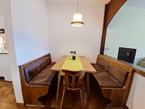 Ein Essbereich mit einem Holztisch, zwei Bänken, einer Hängelampe und einem kleinen Topfpflanzen.