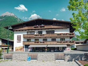 Ein mehrstöckiges Gebäude mit Balkonen, einem gut sichtbaren Eingang und einem Berg im Hintergrund.