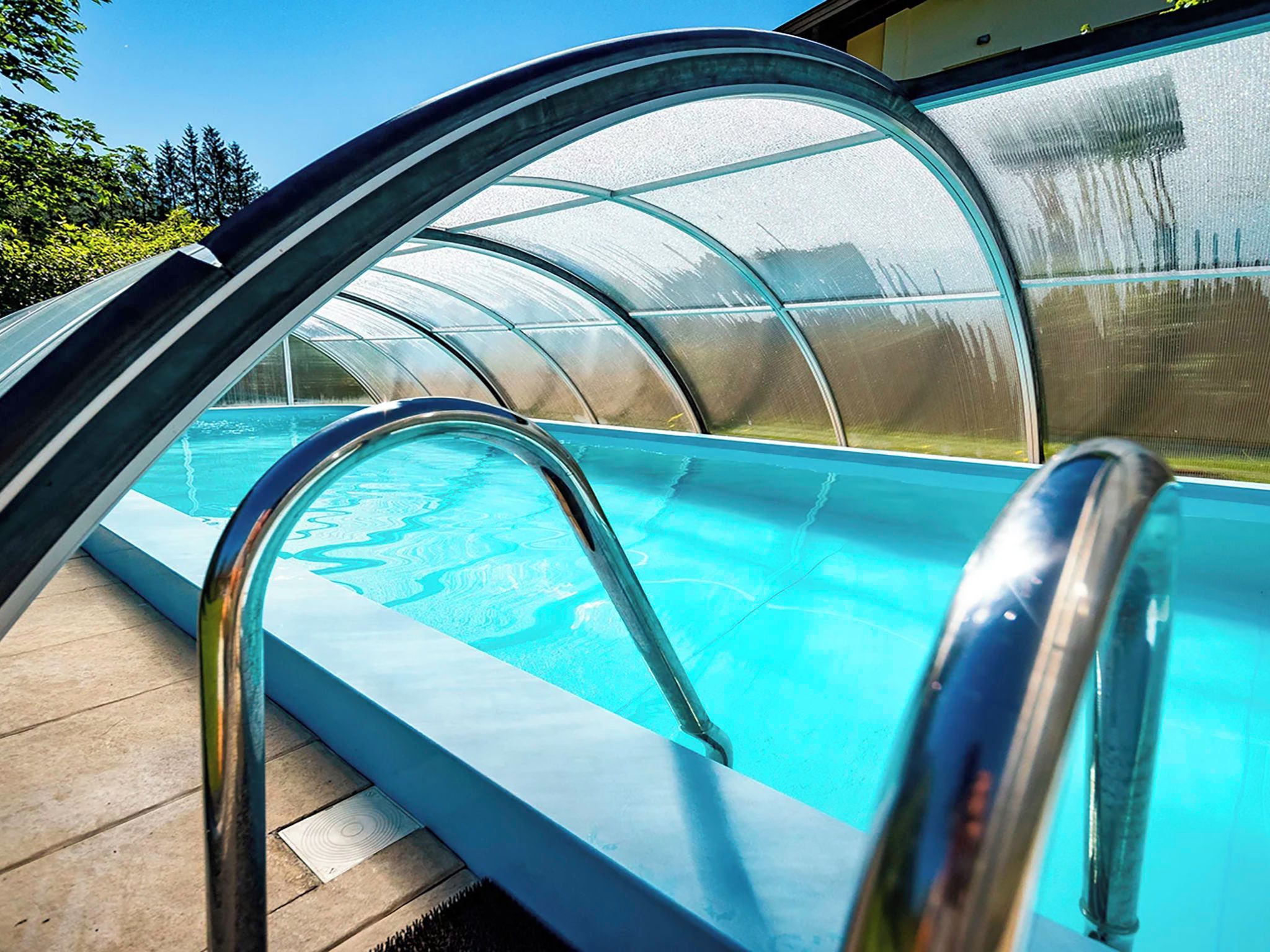 Une piscine dotée d’une enceinte en verre et de rampes métalliques.