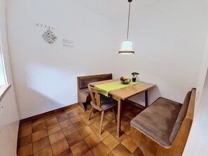 Ein Essbereich mit einem Holztisch, Stühlen, einer Bank, einer hängenden Leuchte und einem kleinen Topfpflanzen.