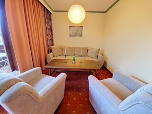 Ein Zimmer mit einer Sofaecke, einem Tisch und einer Pendelleuchte.
