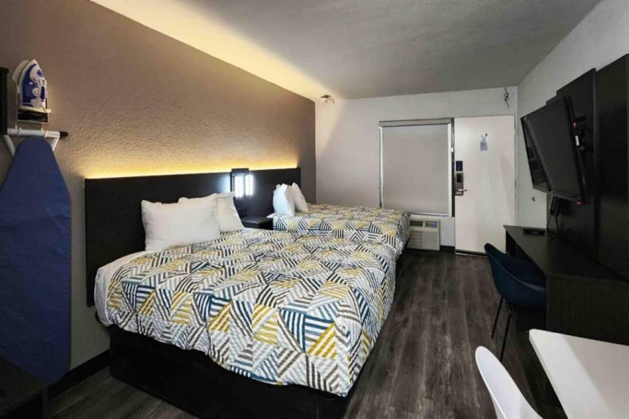 A hotel room with a bed, a desk, a chair, a TV, and a wardrobe.