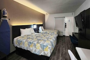 Una habitación de hotel con cama, escritorio, silla, televisión y armario.