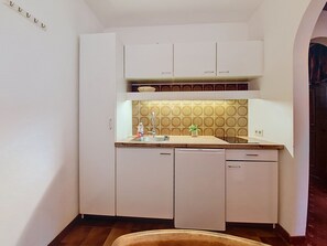 A compact kitchen with white cabinets, a sink, and a dishwasher. - Apartment Arnika by Interhome (Sankt Ulrich am Pillersee)