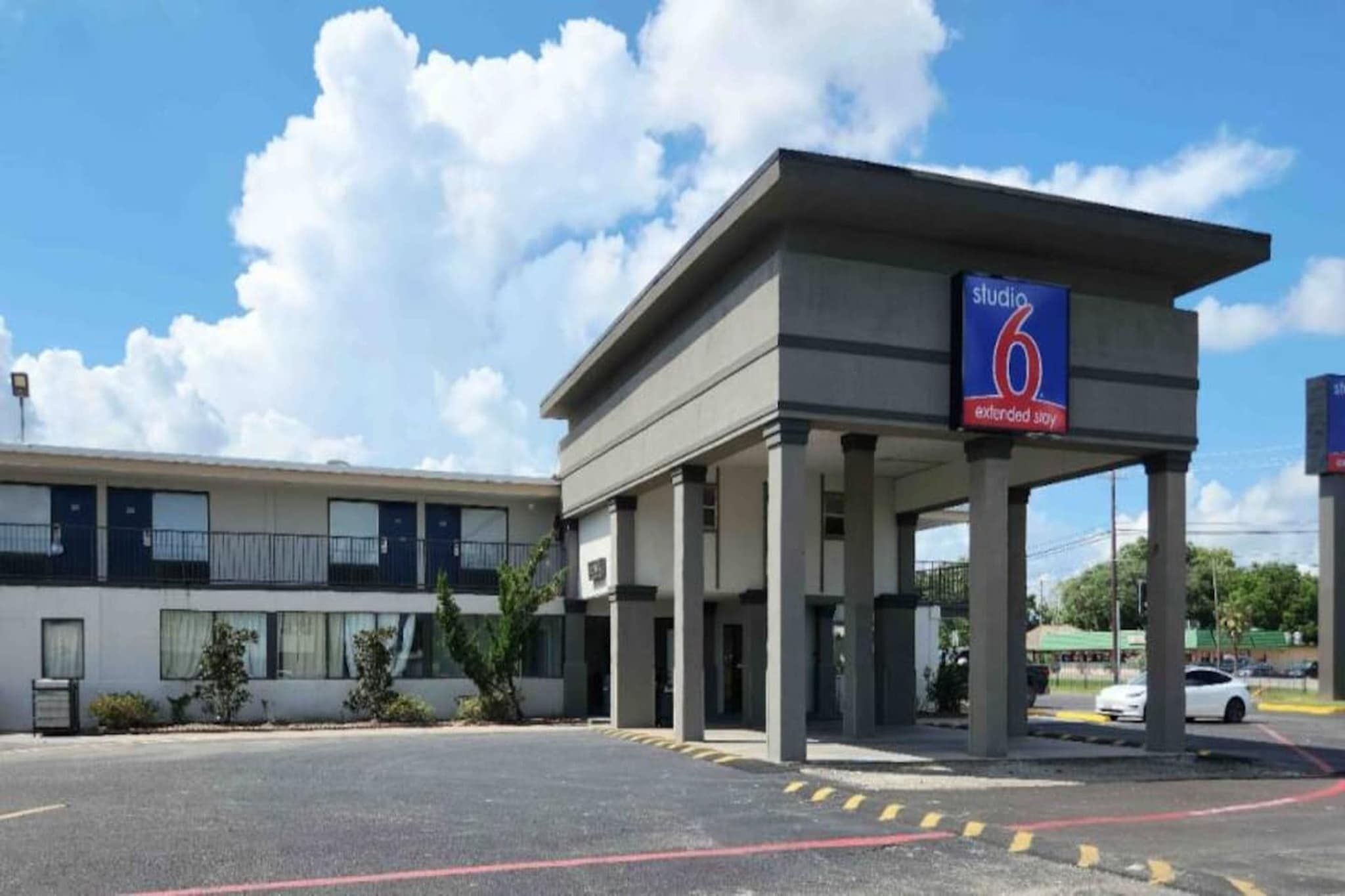 Ein Hotel mit überdachter Eingangspartie, einer Studio 6 Extended Stay Beschilderung und einem Parkplatz mit eingezeichneten Stellplätzen.