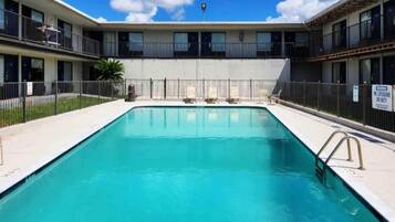 A rectangular swimming pool with a metal ladder on one side, surrounded by a fence.