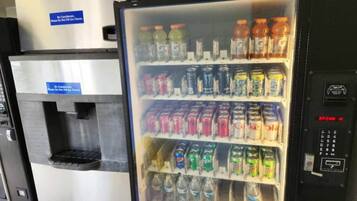 Máquina expendedora de bebidas con varias opciones, incluyendo refrescos y agua.