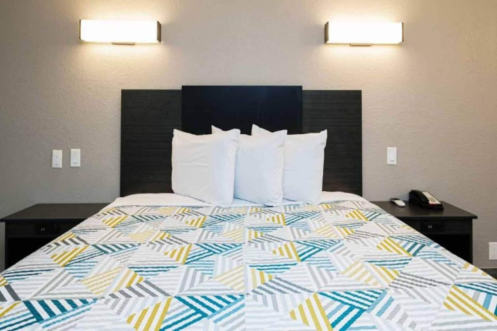 A hotel room with a bed, two bedside tables, and two wall-mounted lamps.