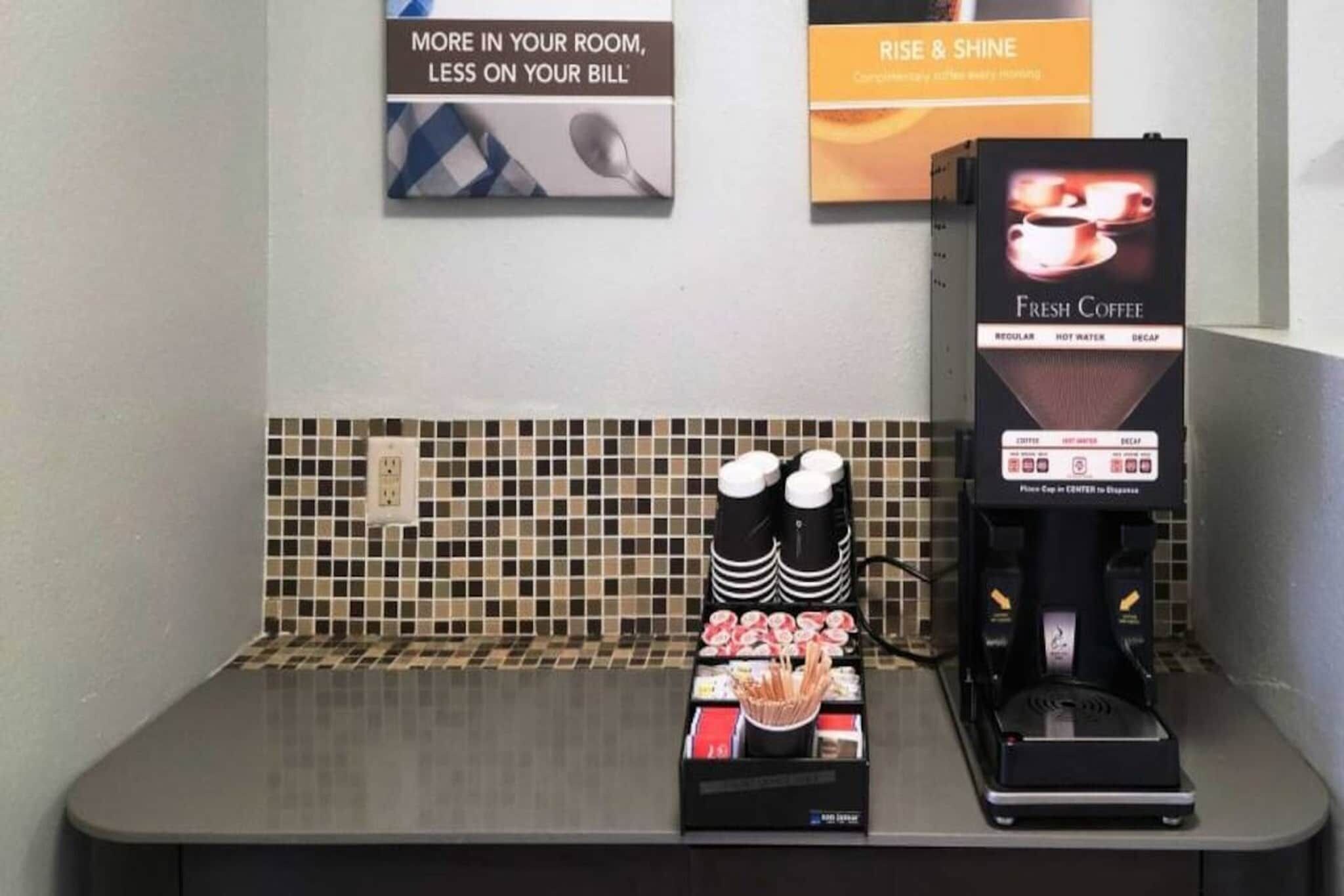 A coffee station with a coffee machine, cups, and condiments.