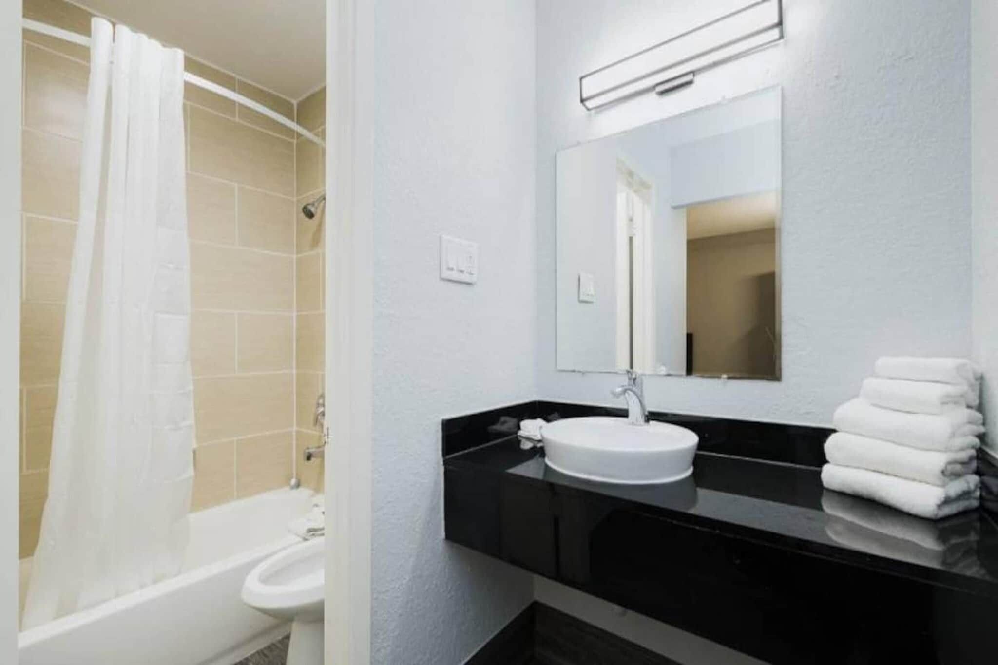 A bathroom with a bathtub, a sink, and a mirror.