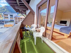 A balcony with a table and chairs, a bed, and a TV in a room. - Vergissmeinnicht / App. 209 by Interhome (Sankt Ulrich am Pillersee)