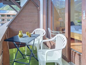 Un balcon avec une table et des chaises, une vue sur les immeubles et une porte dotée d’un trou de serrure.