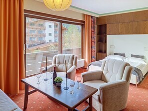 A hotel room with a balcony, a sofa, a table with wine glasses, and a bed. - Alpenrose / App. 208 by Interhome (Sankt Ulrich am Pillersee)