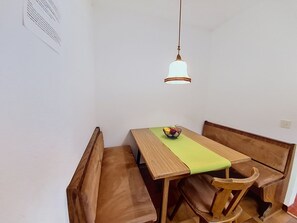 A dining area with a wooden table and benches, a hanging light fixture, and a wall-mounted sign. - Alpenrose by Interhome (Sankt Ulrich am Pillersee)