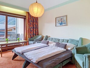 Een hotelkamer met een bed, een bureau, een stoel, een raam met gordijnen, een schilderij aan de muur en uitzicht op het omliggende landschap.