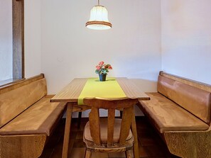 A wooden dining table with a bench on each side, a small potted plant on the table, and a hanging light fixture above. - Seerose by Interhome (Sankt Ulrich am Pillersee)
