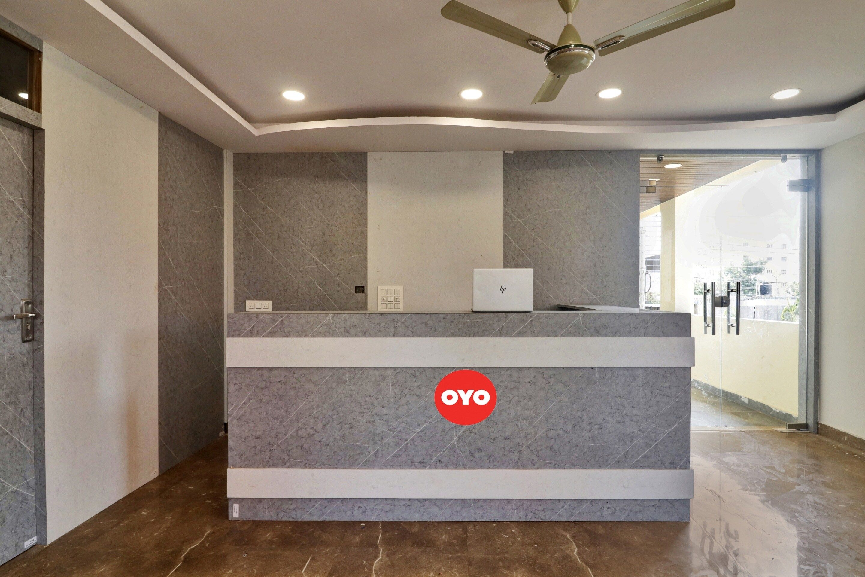 A reception desk with a logo, a ceiling fan, and a glass door leading to another area.