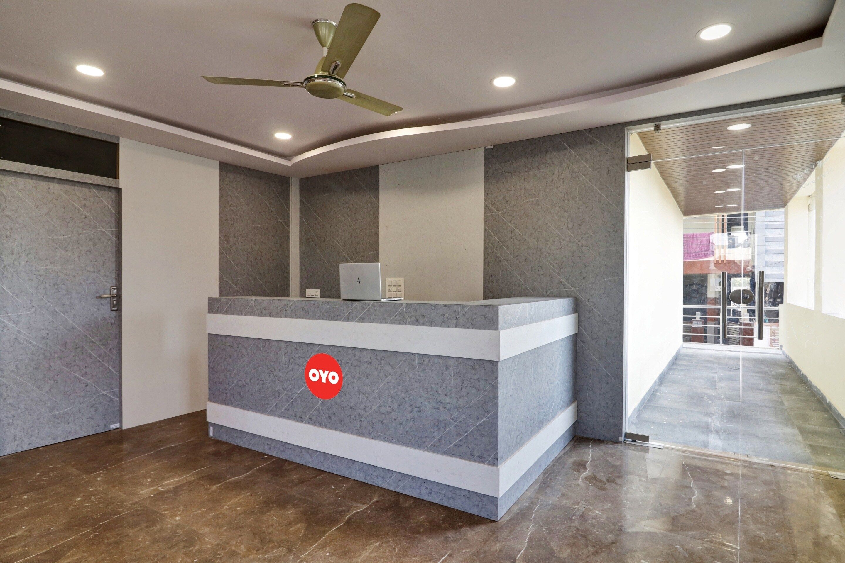 A reception desk with a logo, a ceiling fan, and a view of a corridor.
