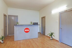 Balcão de recepção com um logotipo, duas plantas em vasos e três portas.