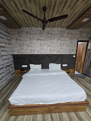 Ein Schlafzimmer mit Holzkopfstütze, Deckenventilator, Wand mit Muster und Bett mit weißer Bettwäsche.