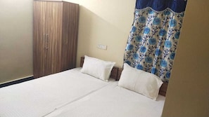 A room with a bed, two pillows, a wardrobe, and a curtain. - Hotel O White Carnations Hotels (Hyderabad)