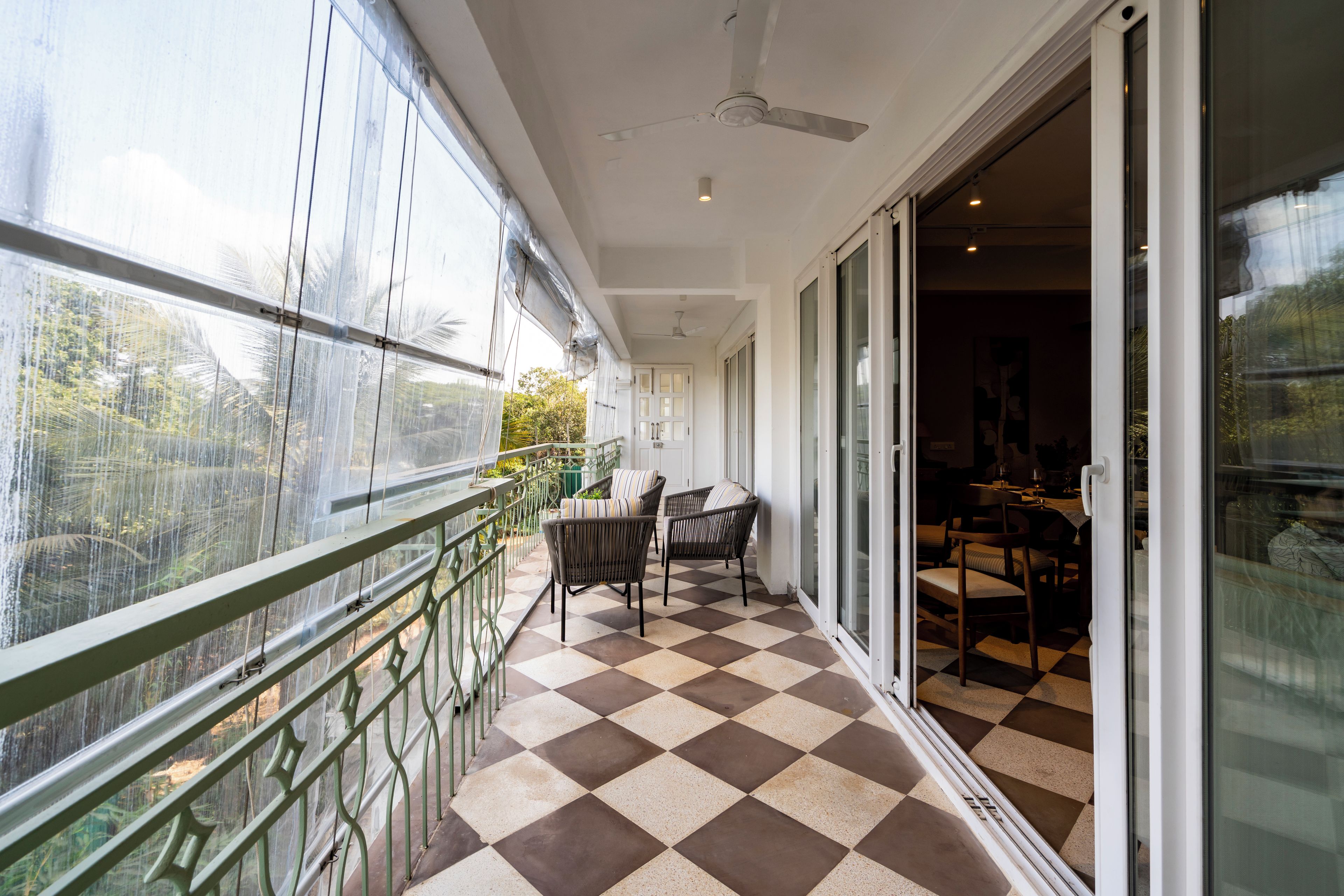 A balcony with a checkered floor, chairs, and a railing.