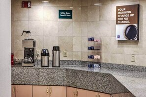 A kitchen area with coffee machines, a sign indicating coffee hours, and a wall-mounted coffee dispenser. - 1 King Bed | Non-Smoking, Kitchen (Dallas)