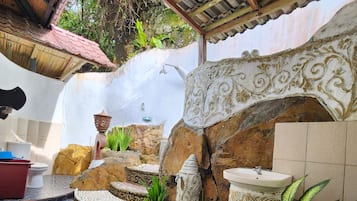 A bathroom with a stone floor, a sink, a toilet, and a shower area.
