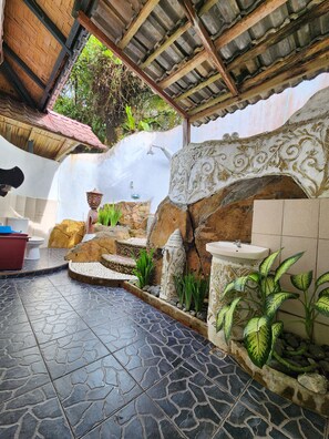 A bathroom with a stone floor, a sink, a toilet, and a shower area.