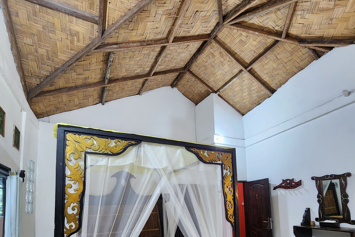 A room with a bed, a mosquito net, a wooden ceiling, and a tiled floor.