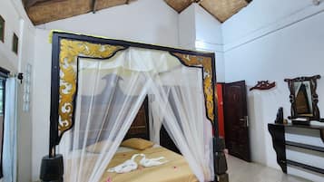 A room with a bed, a mosquito net, a wooden ceiling, and a tiled floor.
