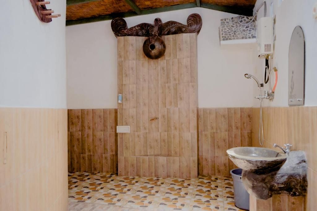 A bathroom with a wooden door, a sink, and a shower.