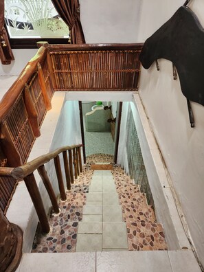 Una escalera con barandilla de madera y piso de baldosas.