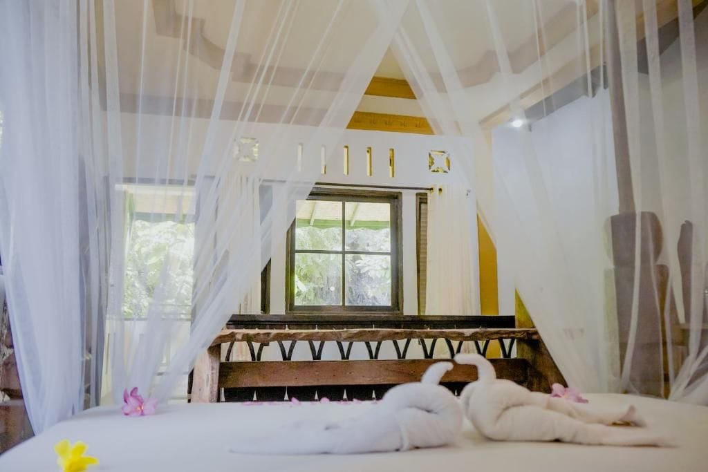 Una habitación con una cama, una ventana y un banco de madera.