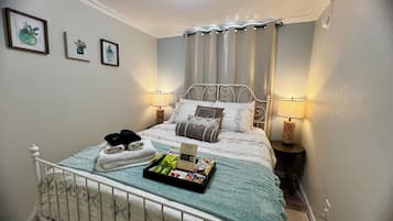 Een net opgemaakt bed met kussens, een dienblad met snacks en een set handdoeken.