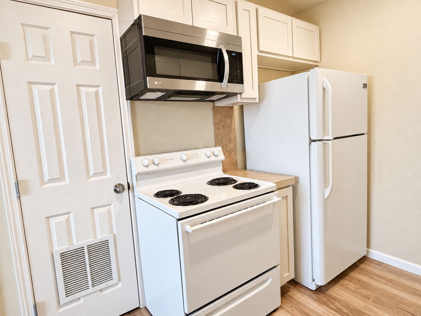 A kitchen with a white stove, a microwave, and a refrigerator.