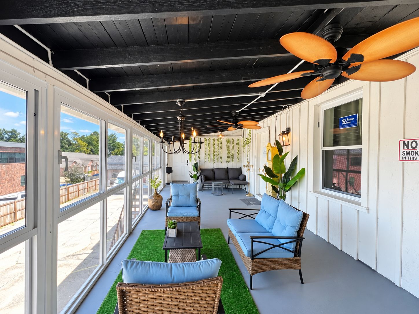 An outdoor covered patio with wicker furniture, ceiling fans, and hanging plants.