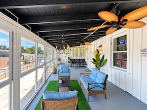 Een overdekt terras buiten, met rieten meubels, plafondventilatoren en hangplanten.