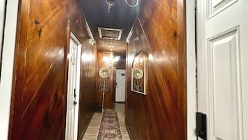 A hallway with wooden walls, a patterned carpet, and a chandelier.