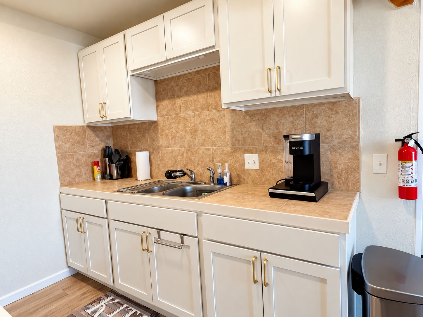 A modern kitchen with white cabinets, a coffee maker, and a fire extinguisher.